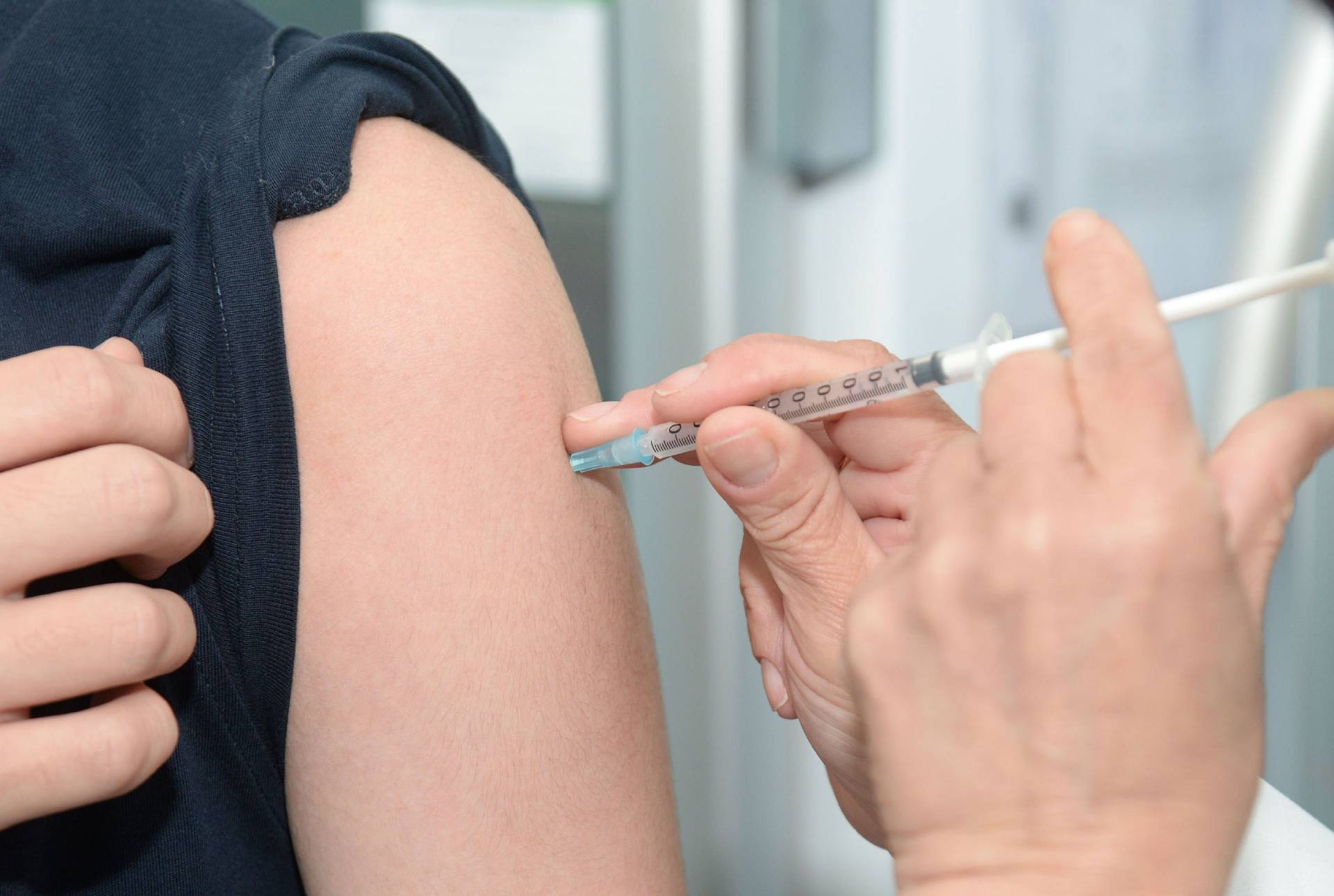 Picture of a woman with sleeve rolled up and a man holding a syringe administering a vaccination
